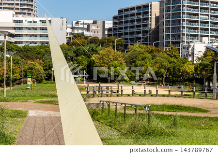公園裡的日晷紀念碑和遠處的公寓大樓群。 公園裡的日晷紀念碑和遠處的公寓大樓群。 143789767