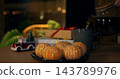 Steaming tea fills ceramic mug next to plate of peeled citrus fruits during festive evening. Wrapped presents with ribbons and toy car ornament establish warm cozy christmas ambiance at home. 143789976