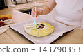 Sweet tart. Glazing pie crust. Woman baker hand brushing round galette with liquid yellow egg wash on baking sheet at home kitchen. 143790353