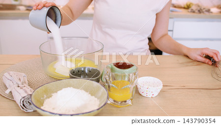 Home recipe. Dessert preparation. Baker female adding measured sugar egg to bowl with batter on table with baking ingredient dish. Home recipe. Dessert preparation. Baker female adding measured sugar egg to bowl with batter on table with baking ingredient dish. 143790354