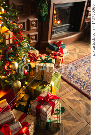 Many gift boxes in classical Christmas decorated interior living room library with fireplace. Christmas gift near fir tree. Modern classic style interior design apartment. Christmas eve at home Many gift boxes in classical Christmas decorated interior living room library with fireplace. Christmas gift near fir tree. Modern classic style interior design apartment. Christmas eve at home 143790360
