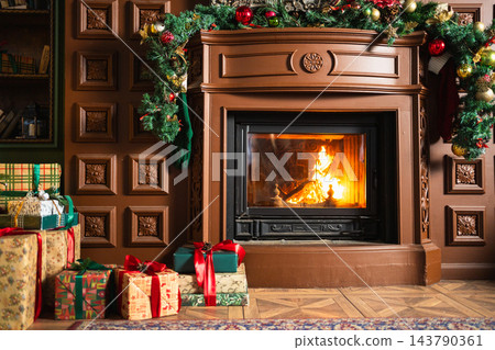 Classical Christmas decorated interior living room with fireplace. Home with Christmas red golden ornament decorations gift boxes. Modern classic style interior design apartment. Christmas eve at home Classical Christmas decorated interior living room with fireplace. Home with Christmas red golden ornament decorations gift boxes. Modern classic style interior design apartment. Christmas eve at home 143790361