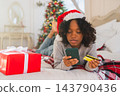 African American woman shopping online holding smartphone paying with gold credit card for Christmas gifts. Girl buying on Internet enter credit card details enjoying Christmas winter holidays at home 143790436