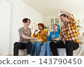 Home party. Cheerful group of friends playing video games at home. Happy diverse group buddies having fun together indoor. Friendship leisure entertainment concept. Young best friends enjoying weekend 143790450