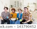 Group of friends watching sport match soccer football game on tv. Happy football fans celebrating victory at home. Friendship sports entertainment concept. Diverse buddies having fun together at home 143790452