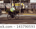 The back view of a parking enforcement officer crossing an intersection 143790593