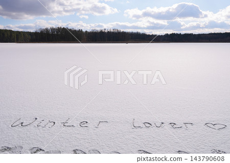 Written WINTER LOVER on snow background message ice outdoor on ground in winter. Writing text sign and drawing on field in frozen background. Weather is changing cold season has arrived. Mockup Copy Written WINTER LOVER on snow background message ice outdoor on ground in winter. Writing text sign and drawing on field in frozen background. Weather is changing cold season has arrived. Mockup Copy 143790608