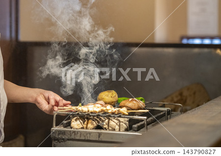 廚師的手正在炭火上烤雞肉串。 廚師的手正在炭火上烤雞肉串。 143790827