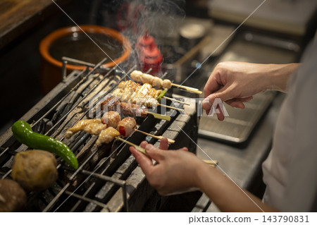 廚師的手正在炭火上烤雞肉串。 廚師的手正在炭火上烤雞肉串。 143790831