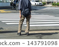 The back view of a young man waiting at a traffic light at an intersection. 143791098