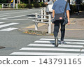 The back view of a young man crossing the sidewalk at an intersection. 143791165