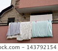 Bedding and sheets drying on a house balcony 143792154