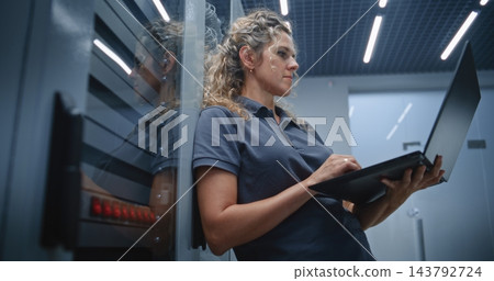 Female Server Room Technician Analyzing Server Performance While Colleague Checks Other Racks 143792724