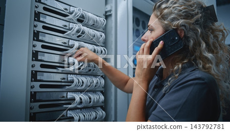 Female IT Specialist Consulting Colleague by Smartphone While Inspecting Server Cable Connections Female IT Specialist Consulting Colleague by Smartphone While Inspecting Server Cable Connections 143792781