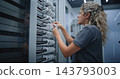 IT Technicians Connecting Network Cables to Separate Server Racks in Data Center 143793003