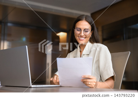 Businesswoman reviewing business documents at office desk Businesswoman reviewing business documents at office desk 143793220