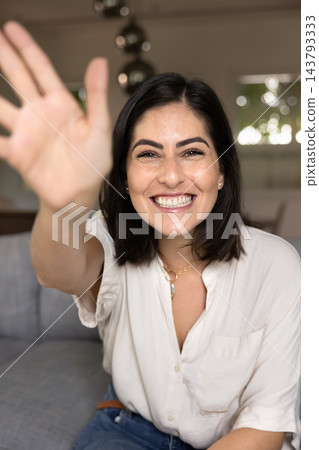Woman looks at camera, greeting friend, participating in virtual meeting Woman looks at camera, greeting friend, participating in virtual meeting 143793333