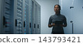Network Engineer Examining Structured Patch Cables and Reviewing Technical Data on Tablet 143793421