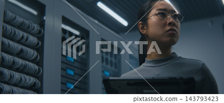 IT Engineer Examining High Density Network Ports, Cable Connections While Reviewing Data on Tablet IT Engineer Examining High Density Network Ports, Cable Connections While Reviewing Data on Tablet 143793423