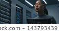 Young Female IT Specialist Reviews Technical Data on Tablet in Modern Server Room. 143793439
