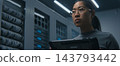 Specialist Inspecting Dense Server Connections and Structured Cabling While Consulting Tablet  143793442