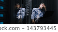 Experienced Network Engineer Working From Server Aisle With Laptop 143793445