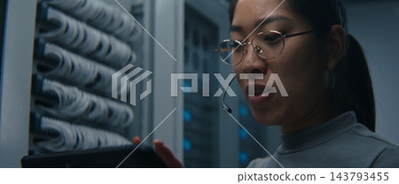 Female Network Engineer Using Tablet and Headset to Coordinate Technical Tasks 143793455