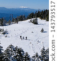 Three hikers walk along a snowfield, with a clear view of snow-capped Mount Ontake from Tsuboniwa. 143793517