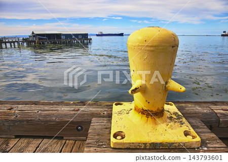 Yellow Mooring Bollard on Wooden Dock with Waterfront and Distant Ships Yellow Mooring Bollard on Wooden Dock with Waterfront and Distant Ships 143793601