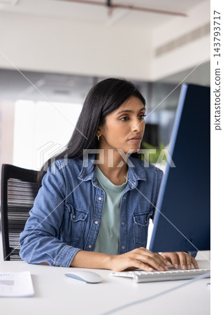 Busy Indian female entering data on computer at office desk Busy Indian female entering data on computer at office desk 143793717