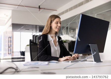 Motivated young female professional working on computer at office desk 143793762
