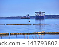 Cargo Ships and Logs on Calm Water with Distant Forest Shoreline in Washington 143793802