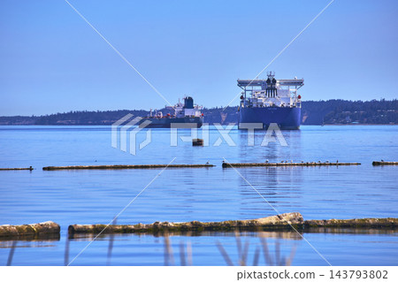 Cargo Ships and Logs on Calm Water with Distant Forest Shoreline in Washington Cargo Ships and Logs on Calm Water with Distant Forest Shoreline in Washington 143793802