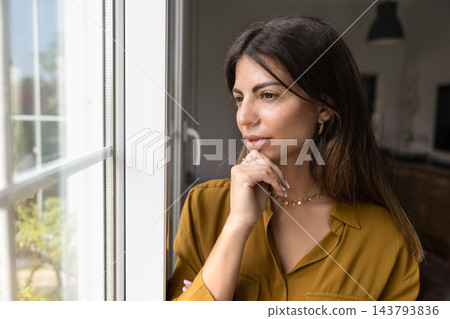 Woman standing next to window, thinking, looking outside Woman standing next to window, thinking, looking outside 143793836
