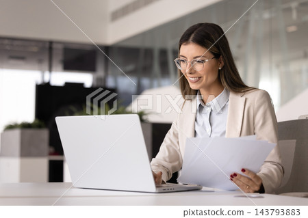 Positive successful financial professional woman in glasses analyzing paper report Positive successful financial professional woman in glasses analyzing paper report 143793883