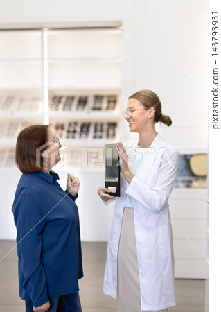 Female optometrist consulting senior woman in optical clinic Female optometrist consulting senior woman in optical clinic 143793931