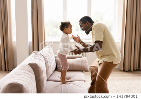 Black father playing with toddler daughter at home 143794001