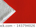 White Paper Towel Corner on Red Background With Embossed Texture Minimalist Cleaning Concept 143794026