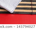 White Paper Napkin On Bamboo Sushi Mat With Red Background For Minimal Table Setting 143794027