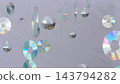 Compact discs and disco balls dangle at various heights in studio setting. Iridescent rainbow reflections shine across smooth shiny surfaces creating festive party atmosphere. 143794282