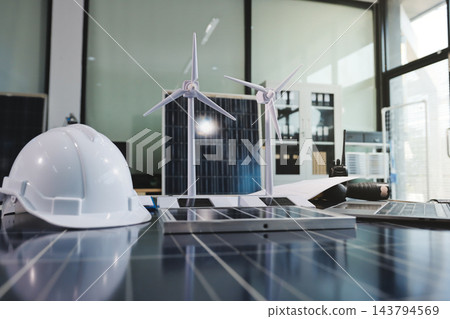 Two Asian engineers wearing hardhats and safety vests discussing solar panel installation and renewable energy project in the office. Two Asian engineers wearing hardhats and safety vests discussing solar panel installation and renewable energy project in the office. 143794569