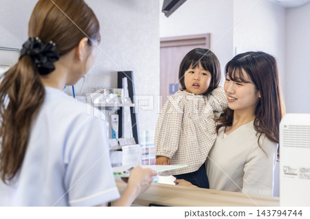 一位母親帶著她兩歲的女兒在牙醫診所當接待員。 一位母親帶著她兩歲的女兒在牙醫診所當接待員。 143794744