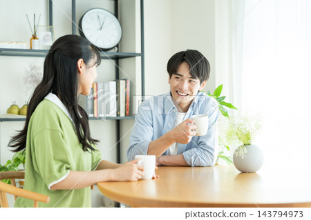 年輕的夫婦在家裡喝咖啡 年輕的夫婦在家裡喝咖啡 143794973