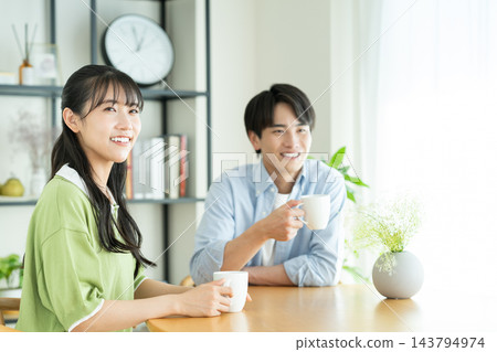 年輕的夫婦在家裡喝咖啡 年輕的夫婦在家裡喝咖啡 143794974