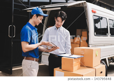 Young businessman signing a delivery receipt document on a clipboard held by a courier in a blue uniform. Young businessman signing a delivery receipt document on a clipboard held by a courier in a blue uniform. 143795648