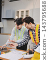 Asian architect and engineer team checking architectural house model using measuring tape on the table at office studio. 143795688