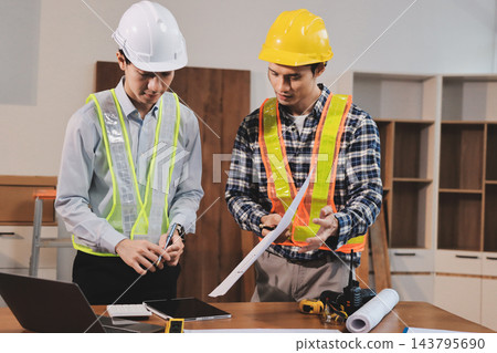 Asian architect and engineer team checking architectural house model using measuring tape on the table at office studio. Asian architect and engineer team checking architectural house model using measuring tape on the table at office studio. 143795690