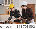 Asian architect and engineer team checking architectural house model using measuring tape on the table at office studio. 143795692