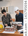 Asian architect and engineer team checking architectural house model using measuring tape on the table at office studio. 143795694