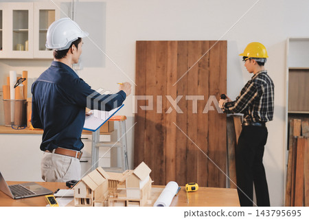 Asian architect and engineer team checking architectural house model using measuring tape on the table at office studio. Asian architect and engineer team checking architectural house model using measuring tape on the table at office studio. 143795695